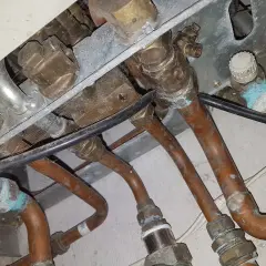 Instalacja pieca gazowego Vaillant z miedzianymi rurami. Widoczne przyłącza i zawory, być może problem ze słabym ciśnieniem ciepłej wody.