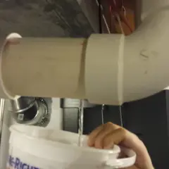 Krople wody z pieca dwufunkcyjnego lądują w wiadrze.