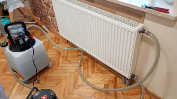 Profesjonalne płukanie instalacji grzewczej w Warszawie. Sprzęt do czyszczenia podłączony do grzejnika.